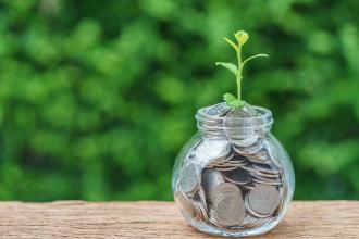 Selective focus on green sprout plant on jar with full of coins